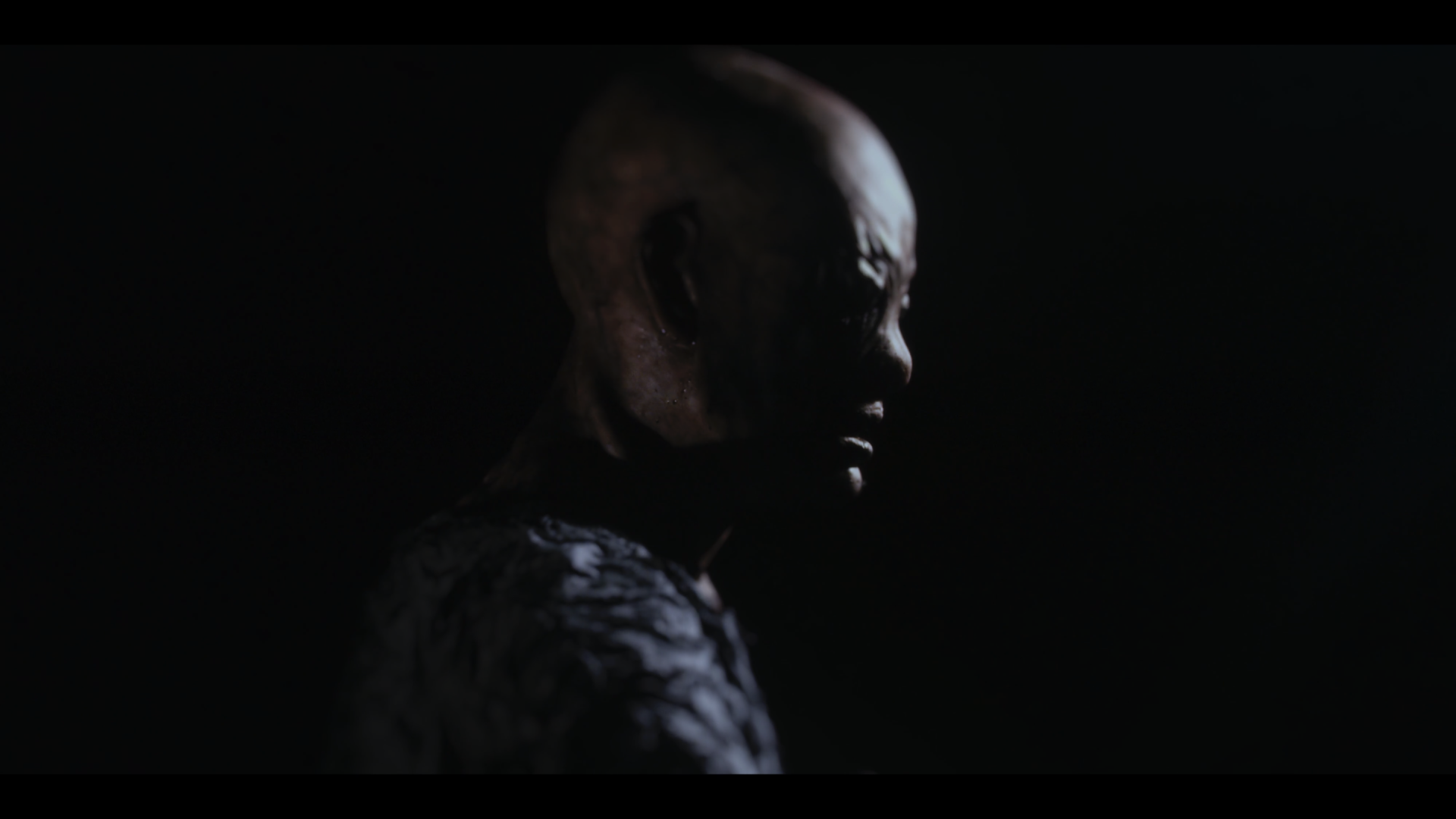 The image depicts the Archon, one of the characters from the film: a figure with a monstrous face shrouded in darkness.