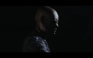 The image depicts the Archon, one of the characters from the film: a figure with a monstrous face shrouded in darkness.